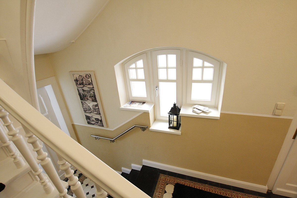Heller Zugang mit Bogenfenster und Treppe zur Souterrain-Wohnung der Villa Emmilio
