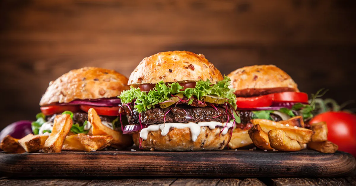 Drei hausgemachte Burger auf einem Holzbrett