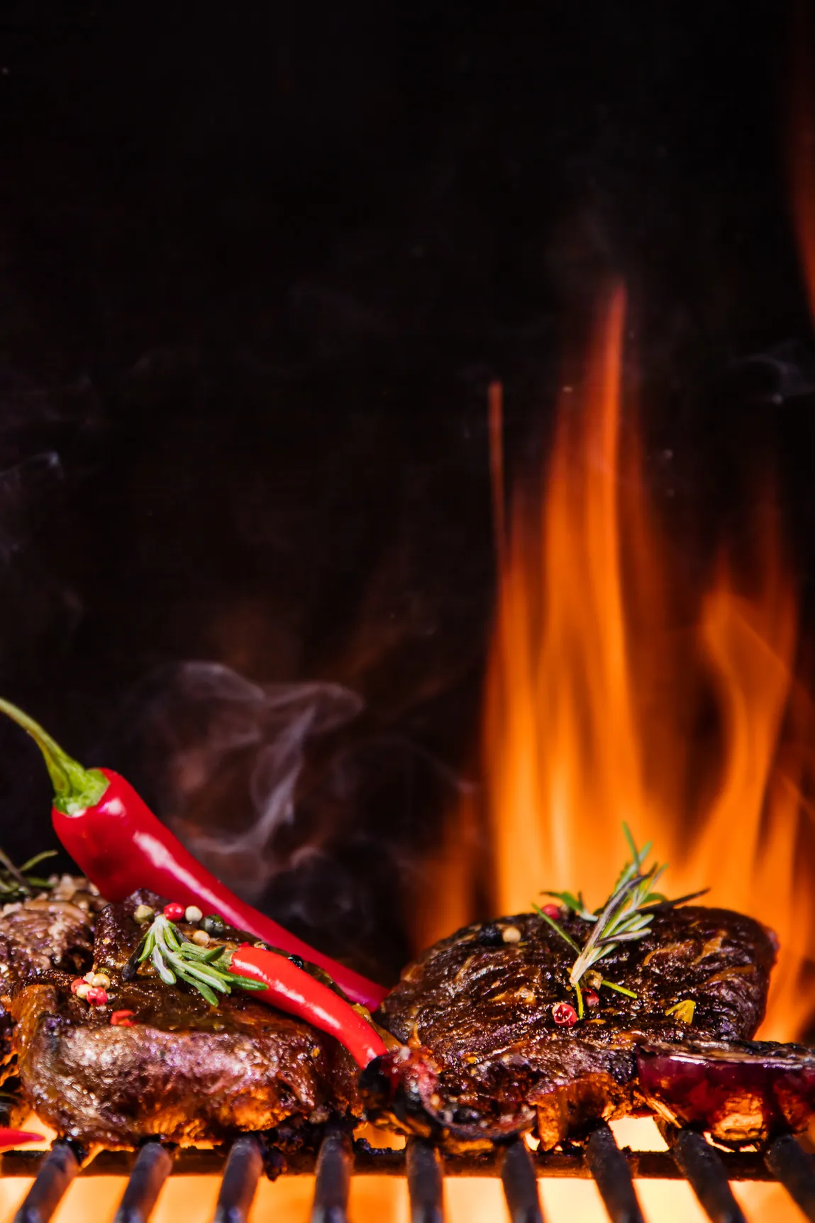 Steaks mit Chili und Rosmarin über offener Flamme auf dem Grill